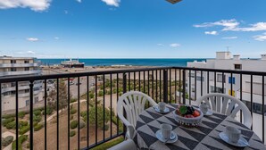 Un balcone con un tavolo apparecchiato per due, con vista sulla costa, edifici e una nave.