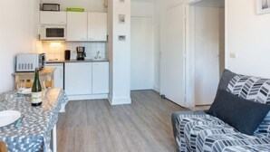 A compact living space with a kitchenette, a dining area, and a sofa. - Fleur Marine by Interhome (Cabourg)