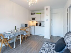 Un espacio habitable compacto con kitchenette, una zona de comedor con mesa y sillas, y un sofá.