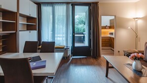 A modern hotel room with a dining area, a kitchenette, and a view of the outdoors.