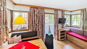 Et værelse med trægulv, sofa, et bord med rød dug, lampe og fjernsyn.