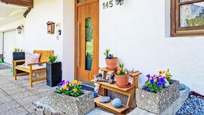 Et hus med en trædør, nummer 145, en bænk og blomsterkasser.