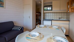 Un ambiente compatto con angolo cottura, un tavolo da pranzo per quattro persone e un divano con un cuscino decorato.