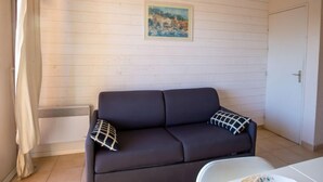 Una stanza con un divano marrone scuro, due cuscini decorati, una porta bianca e un quadro appeso al muro.
