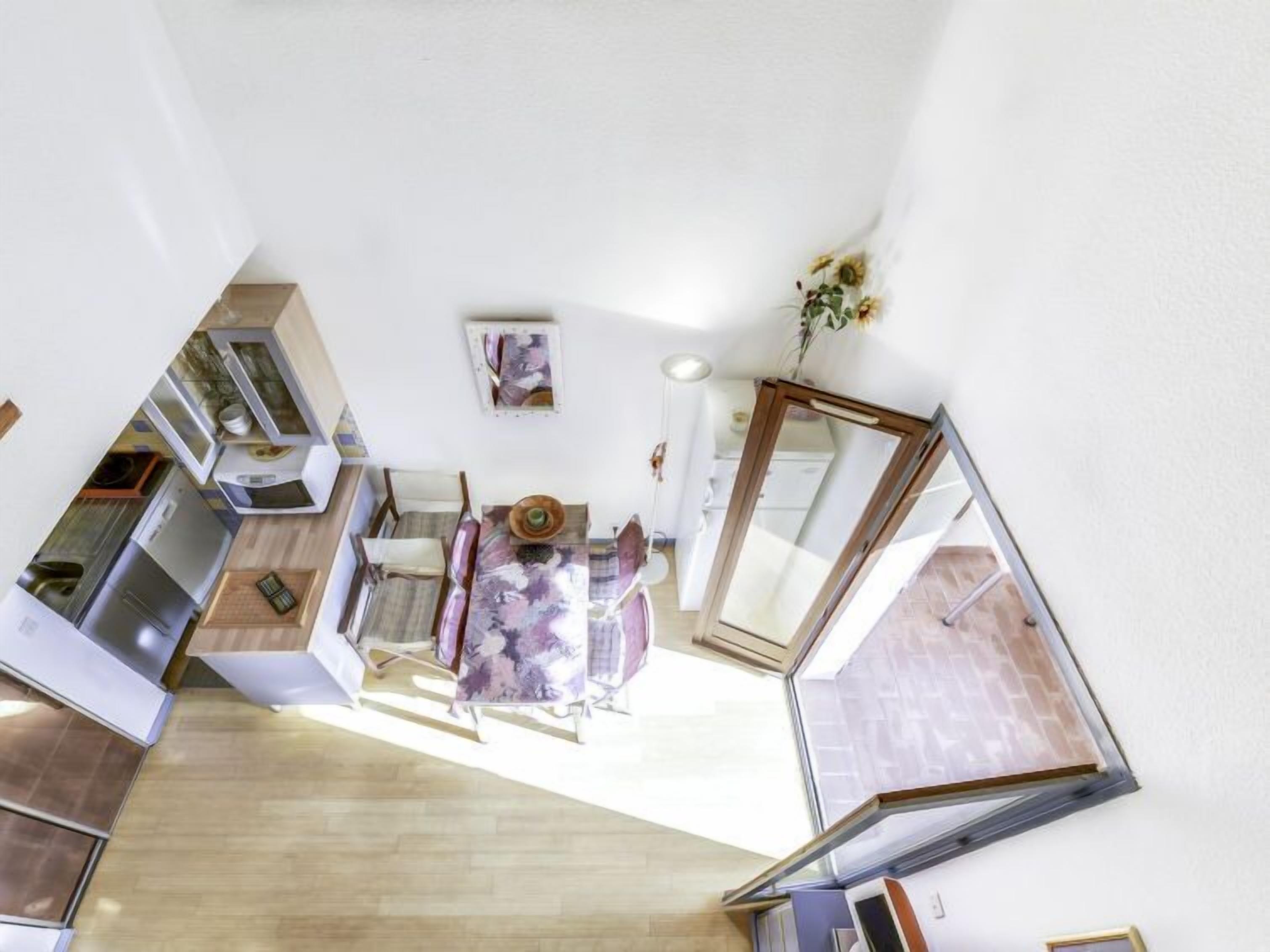 Una cocina moderna con comedor, escalera y un amplio ventanal.