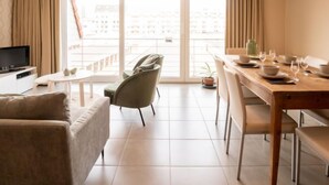 A modern living room with a sofa, TV, and dining area with a table set for two. - Zandloper II with balcony by Interhome (Bredene)