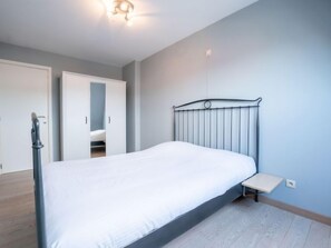 A bedroom with a bed, a bedside table, a wardrobe, and a ceiling light. - Zandloper II with balcony by Interhome (Bredene)
