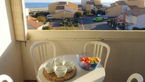 A balcony with a table set for tea, a fruit bowl, and a view of a coastal neighborhood. - Les Balcons de la Méditerranée by Interhome (Narbonne-Plage)