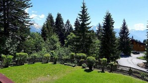 Vista de uma paisagem montanhosa com uma cabana de madeira e uma estrada pavimentada.