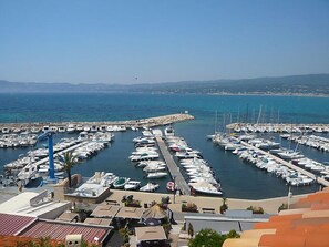 A marina with numerous boats docked, a clear sky, and a view of the coastline.