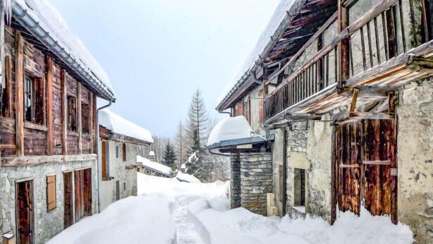 A narrow snow-covered street flanked by wooden buildings with stone walls and traditional architecture. - Chalet Le Tour by Interhome (Argentière)