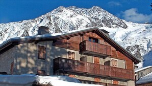 A wooden chalet with balconies, set against a snowy mountain backdrop. - Chalet Le Tour by Interhome (Argentière)