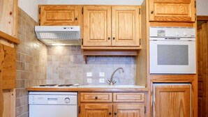 A kitchen with wooden cabinets, a dishwasher, a stove, and a sink. - Chalet Le Tour by Interhome (Argentière)