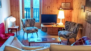 A cozy living room with a sofa, two patterned armchairs, a coffee table, a TV, and a lamp. - Chalet Le Tour by Interhome (Argentière)