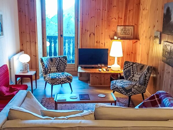 A cozy living room with a sofa, two patterned armchairs, a coffee table, a TV, and a lamp. - Chalet Le Tour by Interhome (Argentière)