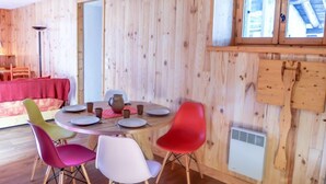 A wooden-paneled room with a round table set for dining, colorful chairs, and a red sofa. - Chalet Le Tour by Interhome (Argentière)