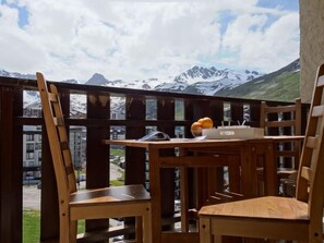 Ein Holzbalkon mit Tisch und Stühlen, mit Blick auf eine Berglandschaft.