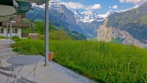 A patio with a table and chairs, overlooking a mountainous landscape with snow-capped peaks. - Silence Apt. H by Interhome (Wengen)