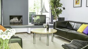 A modern living room with a fireplace, a television, a sofa, and a coffee table. - Vacation home 4L by Interhome (Lochem)