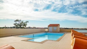 Une piscine située sur le toit d’un petit bâtiment, avec vue sur la mer.