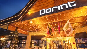 Een hotelingang met een bord waarop 'Dorint' staat en een feestelijke buitenomgeving met lichtjes en sneeuw.