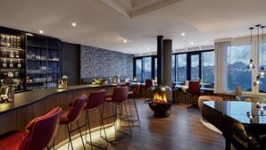 Een moderne bar met een open haard, zitplaatsen en uitzicht op bergen.