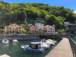 A marina with boats docked, a bridge, and buildings on a hillside.
