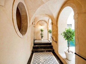 Un couloir orné d’arches, doté d’un sol carrelé et agrémenté de plantes en pot.