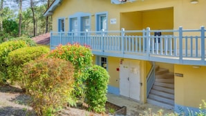 A yellow building with a blue balcony and a staircase leading to a door.