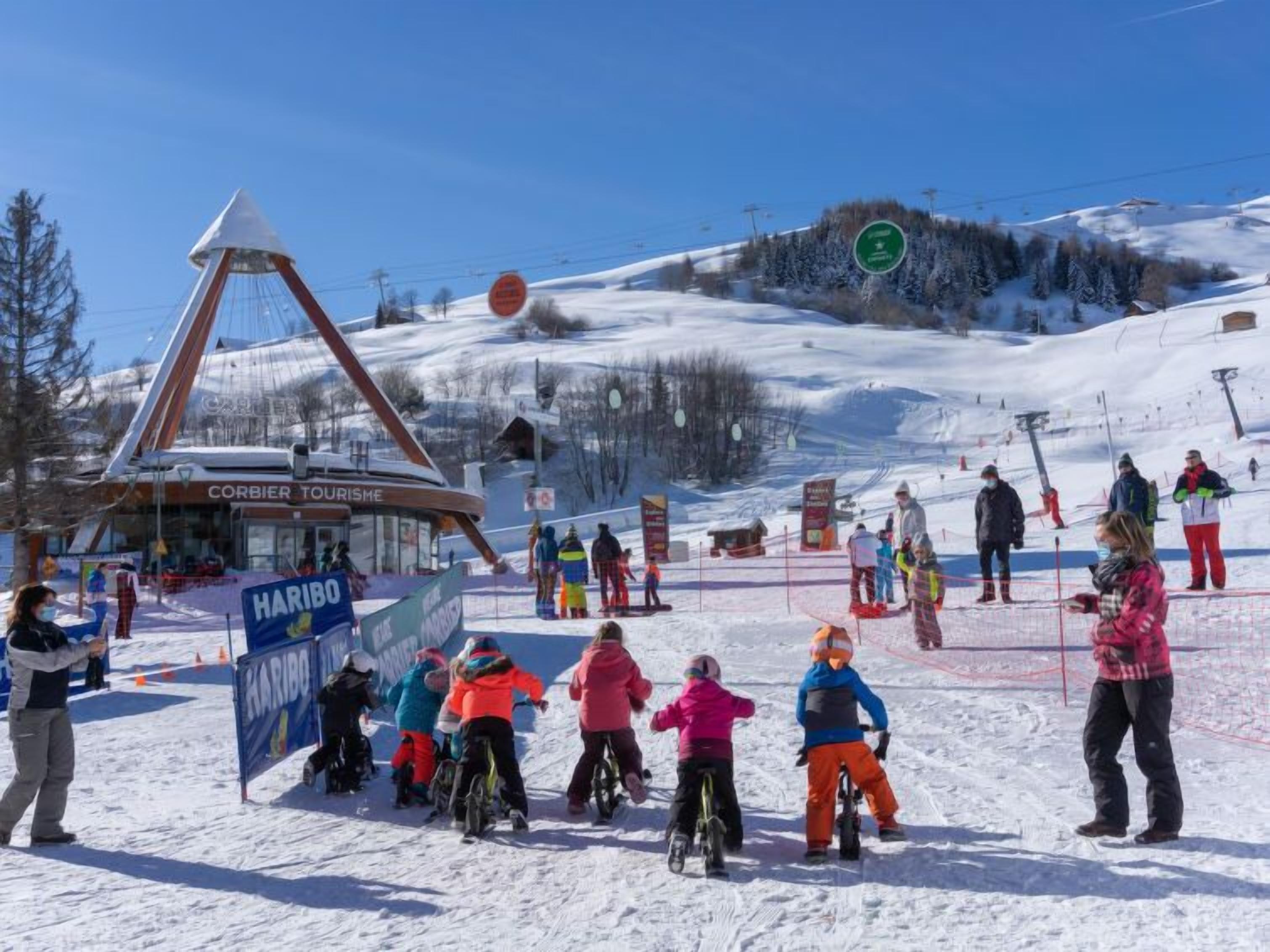 A ski resort with a ski lift, a Corbier Tourisme building, and a Haribo banner.