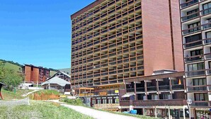 Een meerlaags hotel met een raster van balkons, een bakstenen gevel en een helderblauwe lucht op de achtergrond.