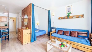 Een gezellige woonkamer met een houten dressoir, een blauwe bank en een salontafel.