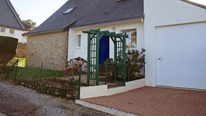Una casa a un piano con facciata in pietra, una porta blu e un portone garage bianco.