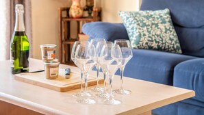 Un soggiorno con un divano blu, un tavolino in legno e una bottiglia di vino.