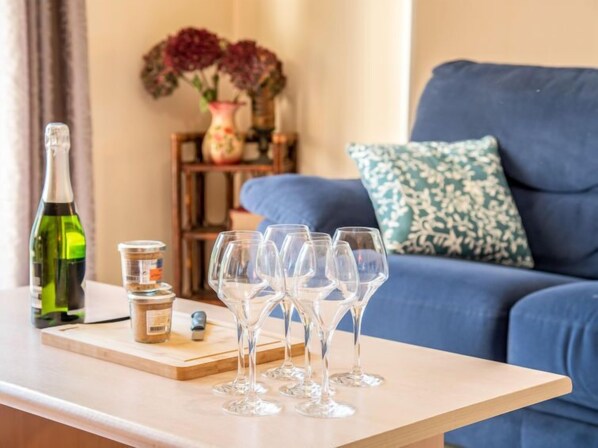 A living room with a blue sofa, a wooden coffee table, and a bottle of wine.