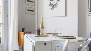 A dining area with a white table, two wine glasses, a bottle of wine, and a small plant. - Le Concordia by Interhome (Nice)