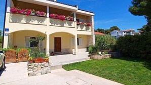A two-story building with a balcony adorned with flowers, a stone entrance, and a well-maintained lawn. - Apartment Ante by Interhome (Brodarica)