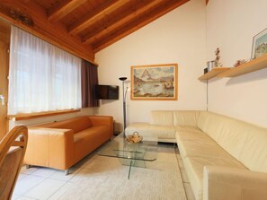 Ein Wohnzimmer mit zwei Sofas, einem Glastisch, einem Bild an der Wand und einem Fernseher über dem Sofa.
