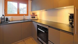 Eine kleine Küche mit Fenster, einer Mikrowelle, einer Kaffeemaschine und einem Geschirrspüler.