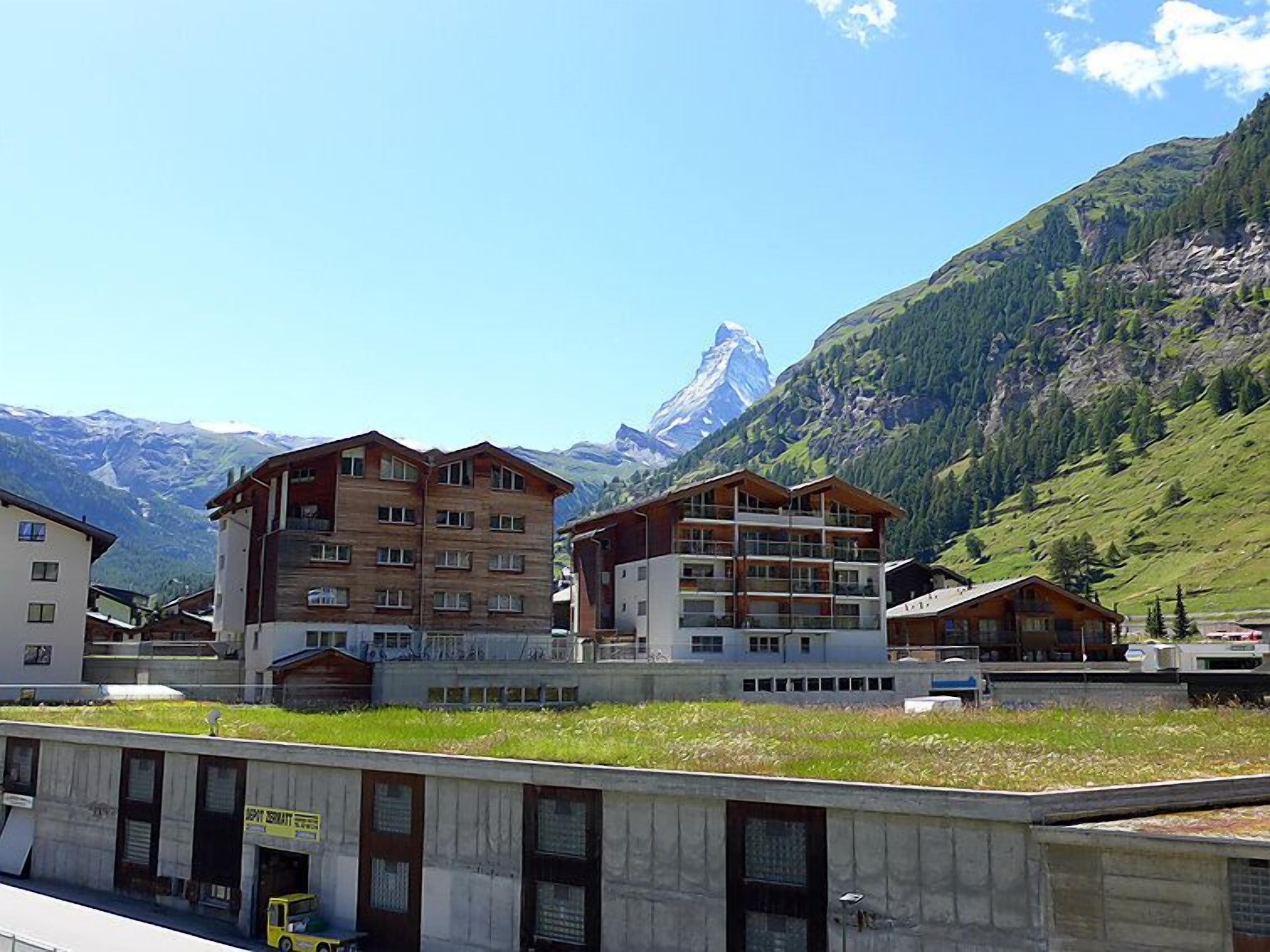 Um hotel com vários andares, um telhado plano e vista para uma montanha.