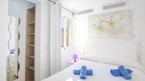 Ein Schlafzimmer mit Bett, Fenster, Tür und einer Wand mit floralem Gemälde.