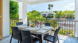 Ein Balkon mit Esstisch, der auf eine Wohngegend mit Bäumen und Häusern blickt.