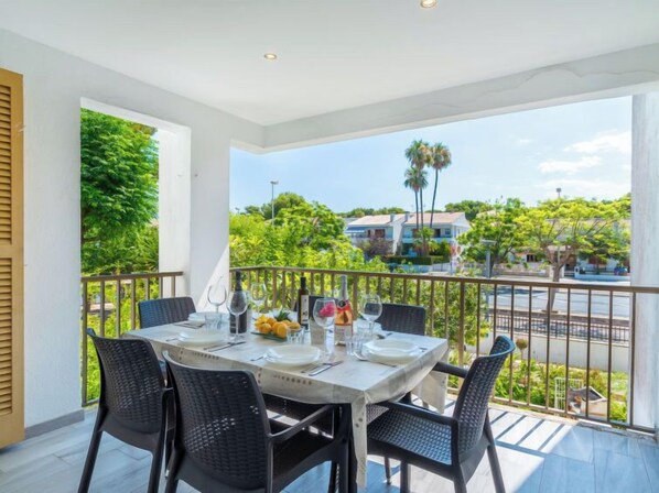 A balcony with a table set for dining, overlooking a residential area with trees and houses.