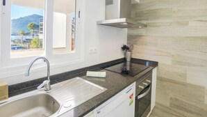 Eine moderne Küche mit Backofen, Spüle aus Edelstahl und einem Fenster mit Blick auf eine reizvolle Landschaft.