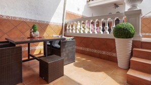 An outdoor patio with wicker furniture, a white balustrade, and a potted plant.