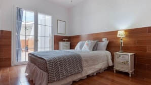 A bedroom with a bed, nightstands, a lamp, and a view through a window.