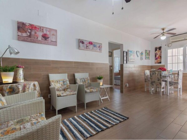 A spacious living area with wicker furniture, a striped rug, and artwork on the walls. - Sagenta by Interhome (Cambrils)