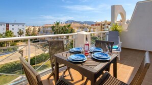 A balcony with a table set for two, overlooking a residential area with palm trees and buildings. - Bahia Blanca by Interhome (Dénia)