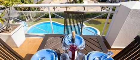 A table set for a meal with a view of a swimming pool and buildings in the background.