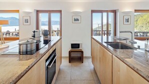 A modern kitchen with granite countertops, stainless steel appliances, and large windows offering mountain views.